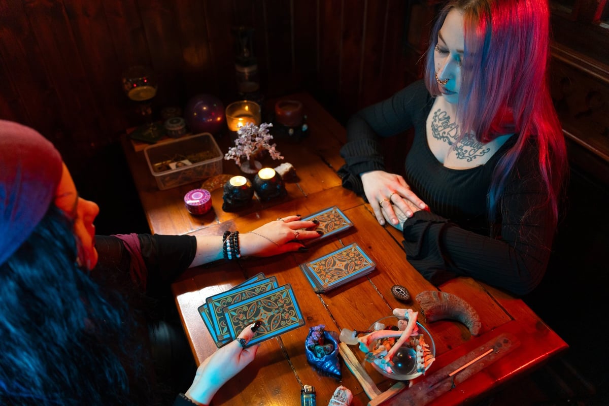 Fortune teller reading tarot cards for a young woman in a mystical setting